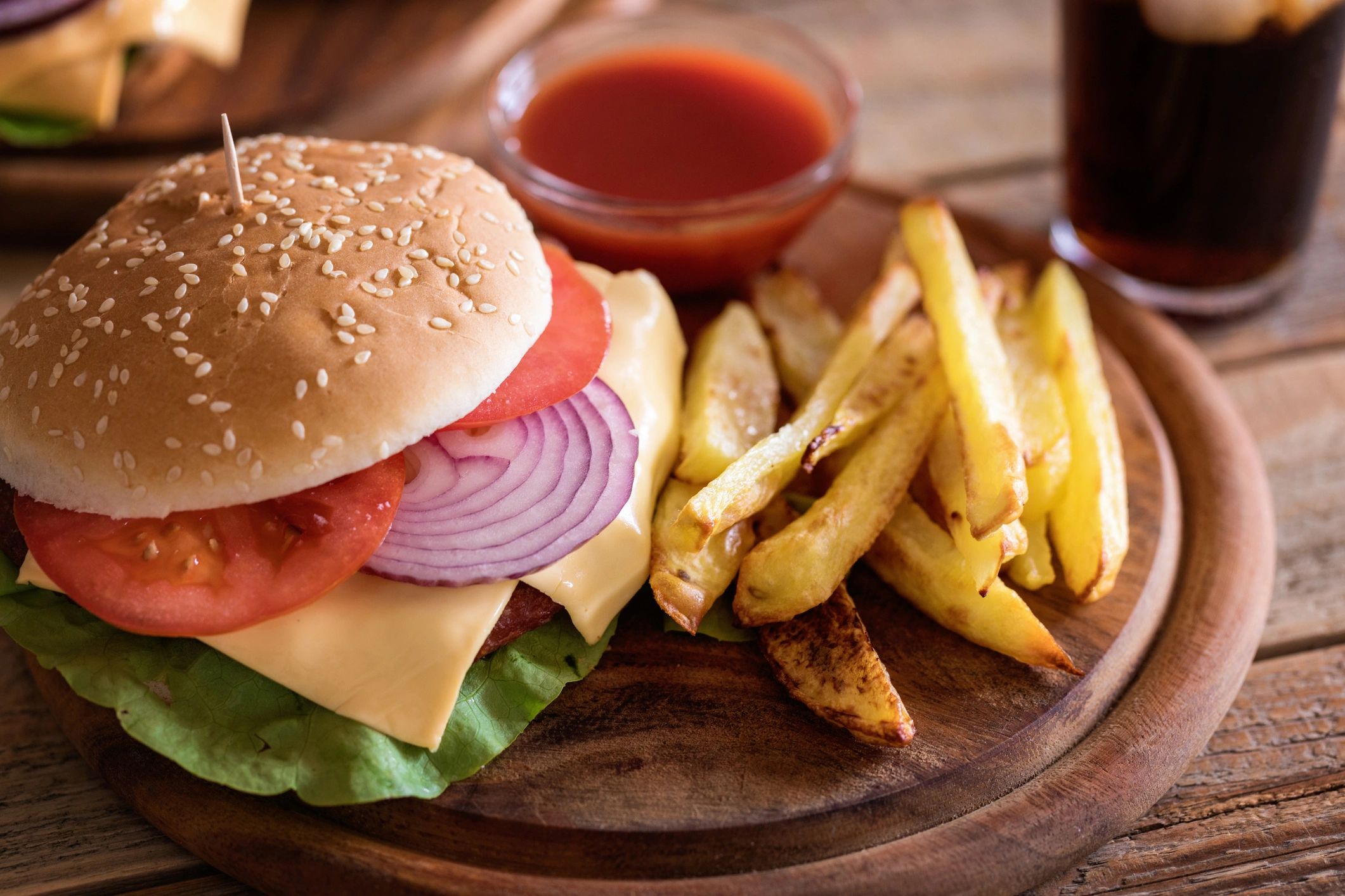 Hamburger with french fries on a wooden plate
